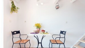 A dining area with a white table, two black metal chairs, and a hanging plant. - Nausica House (Corfu)