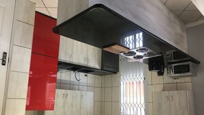 Una cocina moderna con gabinetes grises, una pared de acento roja, un extractor de aire negro y un microondas.