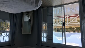 Una habitación con ventanas amplias, una cortina blanca y vistas a un edificio de techo rojo.
