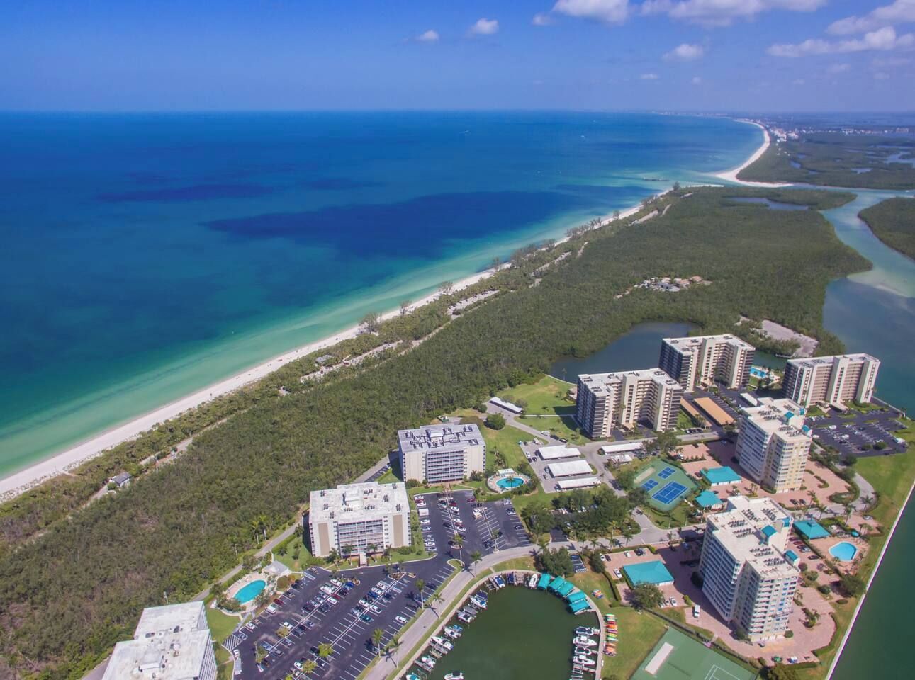 An aerial view of a coastal resort with multiple high-rise buildings, a beach, and a marina.