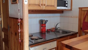 A compact kitchen with wooden cabinets, a microwave, a dishwasher, and a sink.
