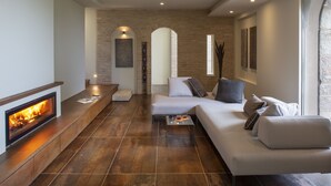 A modern living room with a fireplace, a sofa, a coffee table, and a stone wall. - Villa Fé with swimming pool in Assisi (Assisi)