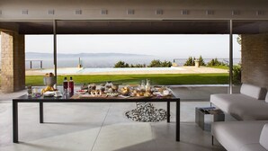 A modern living room with a large glass door leading to a pool area, a dining table set with various dishes, and a comfortable seating area. - Villa Fé with swimming pool in Assisi (Assisi)
