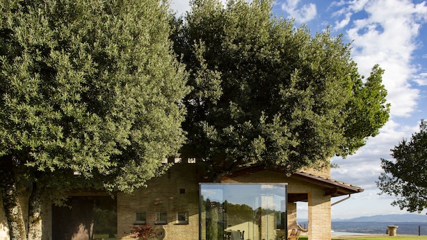 A modern building with a glass facade, surrounded by lush greenery and a clear view of the sky and distant mountains. - Villa Fé with swimming pool in Assisi (Assisi)