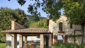 A modern house with a patio, stone walls, and a view of the countryside. - Villa Fé with swimming pool in Assisi (Assisi)