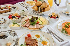 En frukostbuffé med ett varierat utbud av rätter, inklusive ägg, kött, frukt och bakverk.