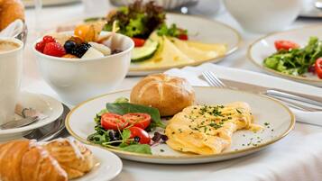 A breakfast setting with croissants, a salad, and a plate with scrambled eggs.