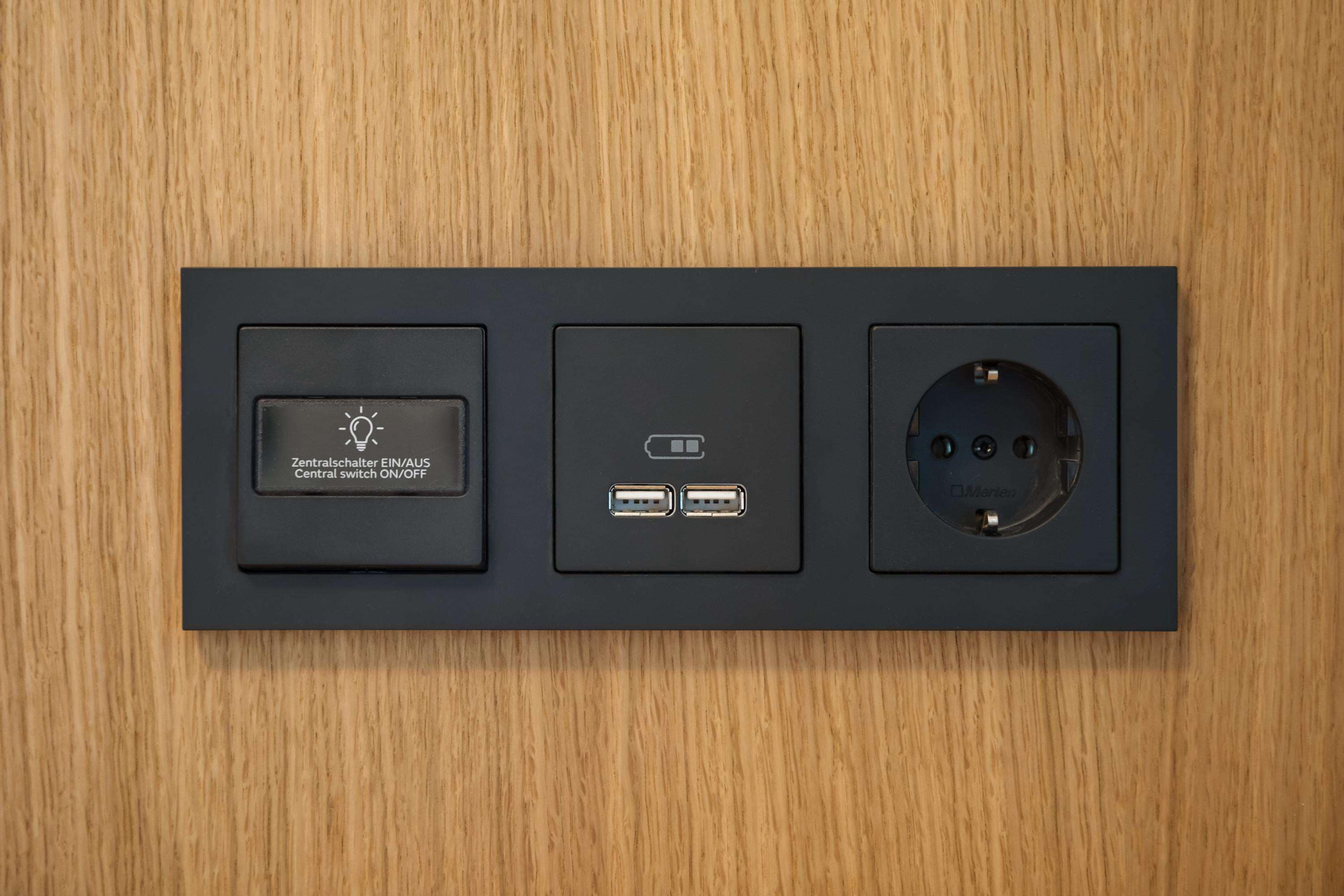 Un panel eléctrico negro con un interruptor central, dos puertos USB y un enchufe.