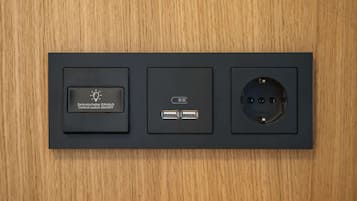 Un panel eléctrico negro con un interruptor central, dos puertos USB y un enchufe.