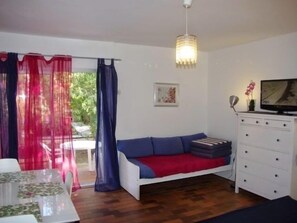 A compact living space with a sofa, a dining table, and a television. - Studio & large garden 200m Calvi beach (Calvi)