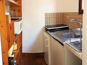 A compact kitchen with a stove, sink, and wooden shelves. - Studio & large garden 200m Calvi beach (Calvi)