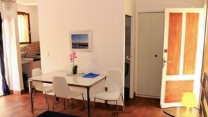 A room with a bed, a dining table with chairs, a small table with a lamp, and a wardrobe. - Studio & large garden 200m Calvi beach (Calvi)