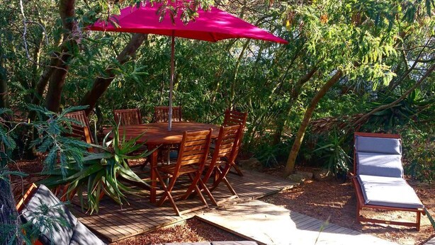 An outdoor patio with a wooden table and chairs, a red umbrella, and a lounge chair. - Studio & large garden 200m Calvi beach (Calvi)