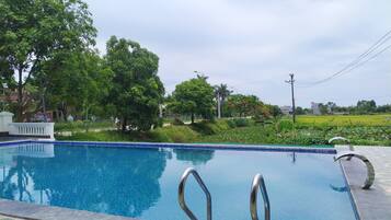 A swimming pool with clear blue water, surrounded by lush greenery and trees.