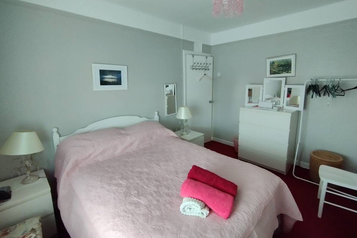 A bedroom with a bed, a dresser, a mirror, a lamp, and a picture on the wall.