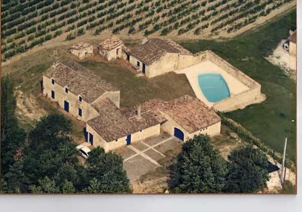 Une vue aérienne d’un bâtiment comprenant de nombreuses pièces, une piscine et, au loin, un vignoble.