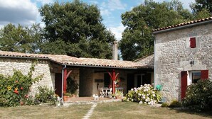 Un edificio in pietra con tetto in tegole, un portico coperto e un vialetto in pietra che conduce all'ingresso.