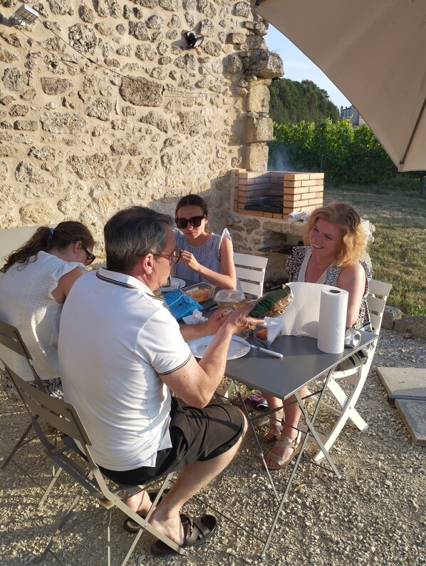 A group of people dining outdoors at a table with a stone wall in the background.