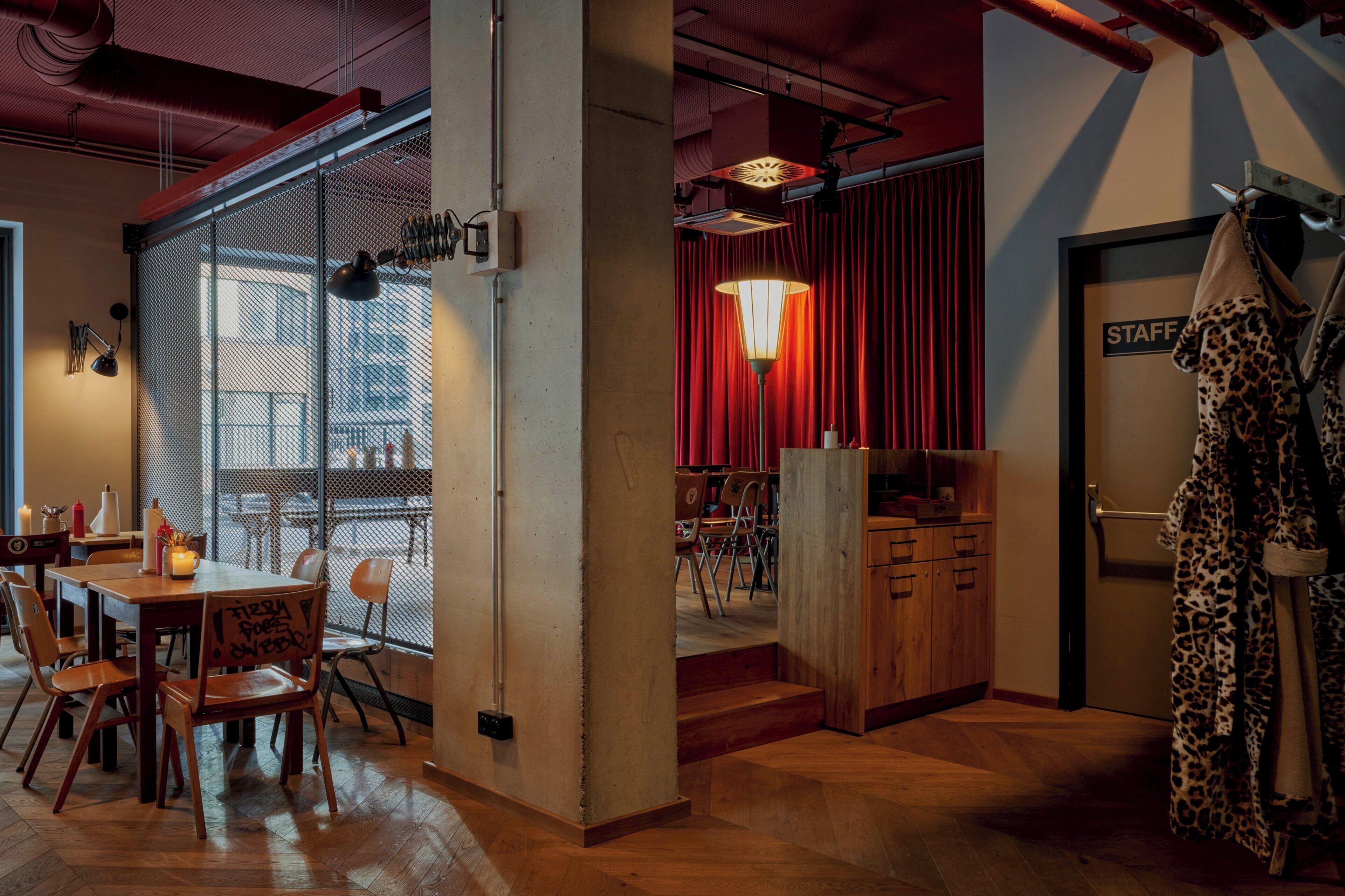 A dining area with a wooden table and chairs, a red curtain backdrop, and a sign labeled "STAFF".