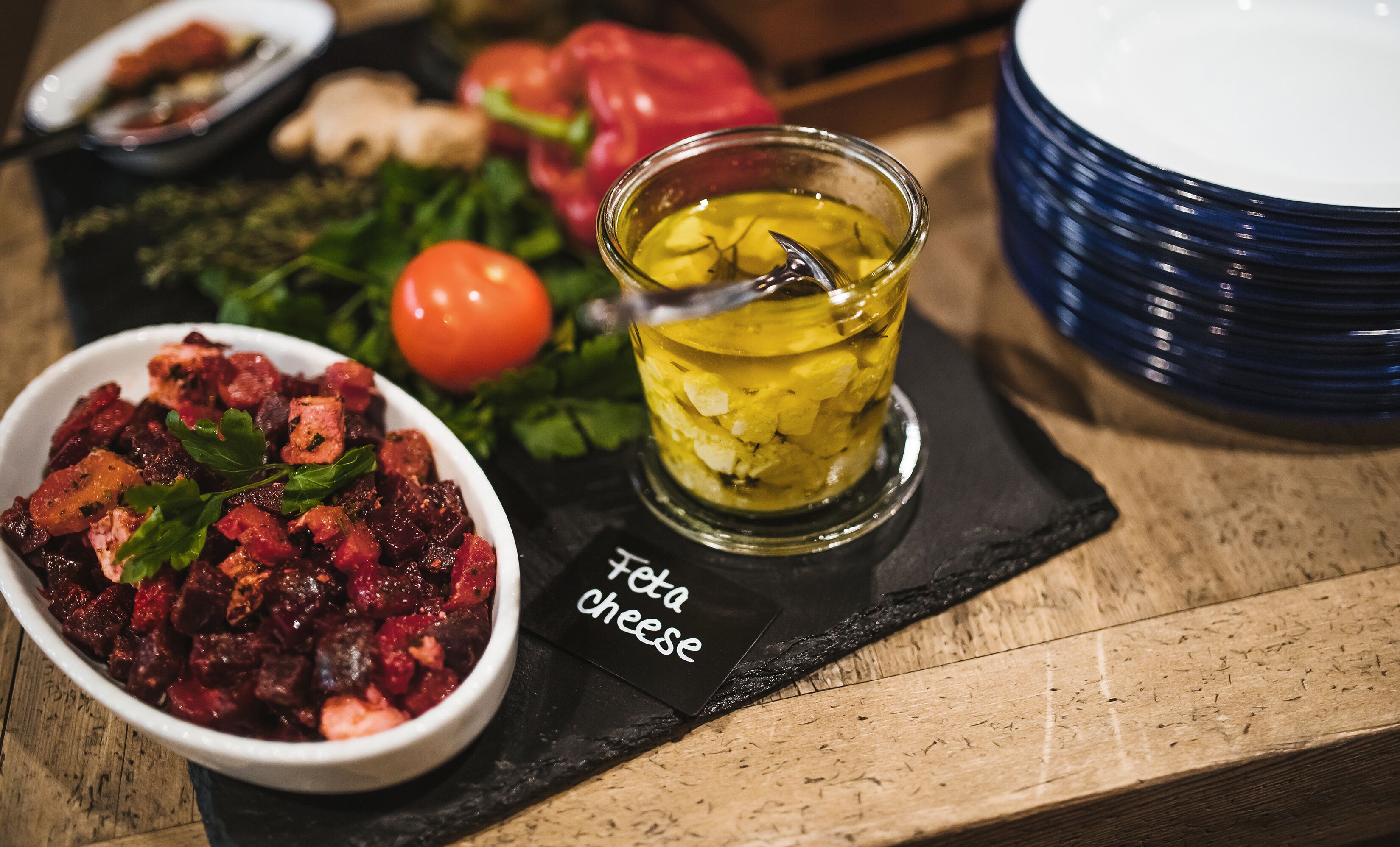 A meal with feta cheese, pickled vegetables, and a tomato on a wooden table.