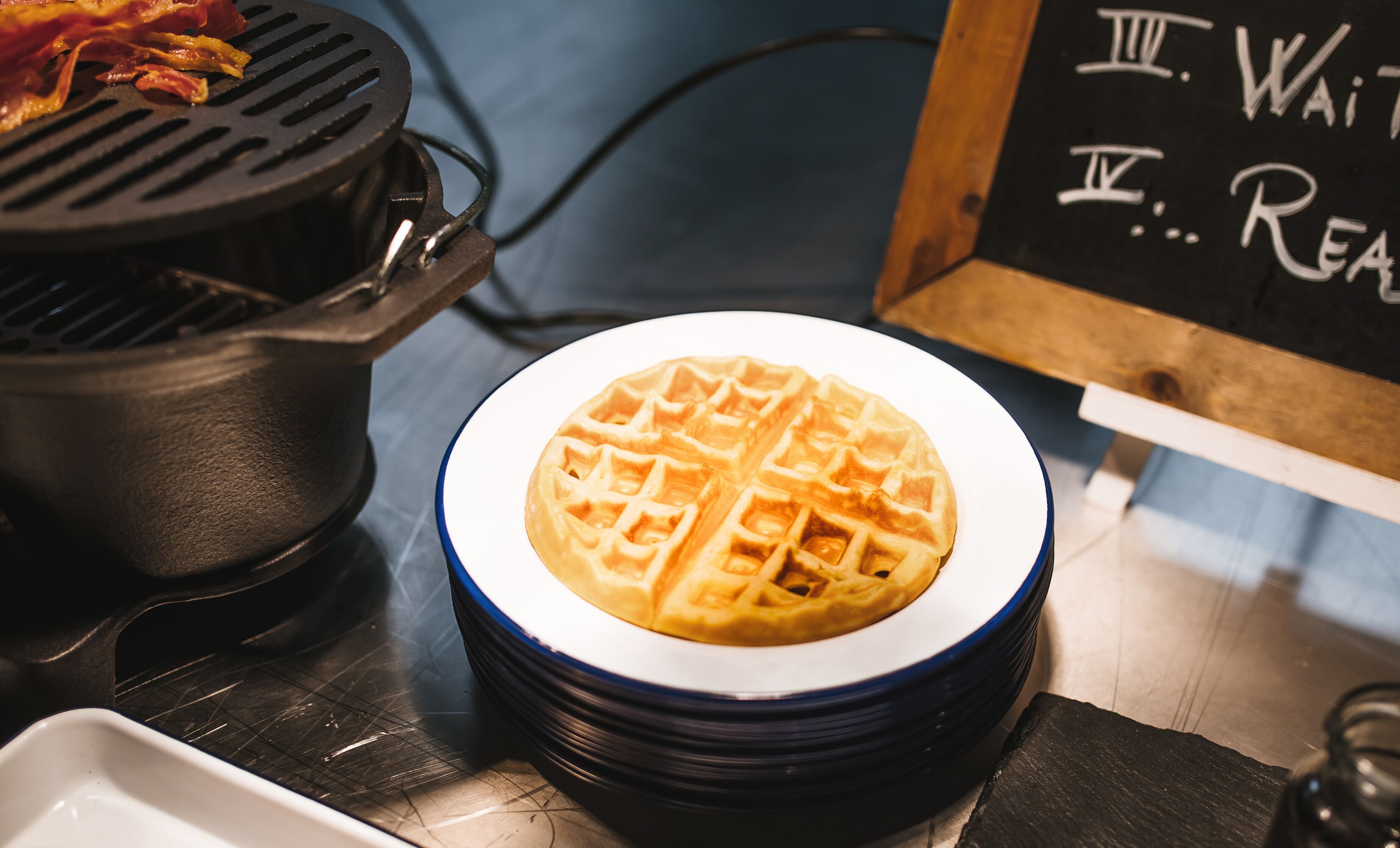 Ein Waffel auf einem Teller, im Hintergrund eine Tafel.