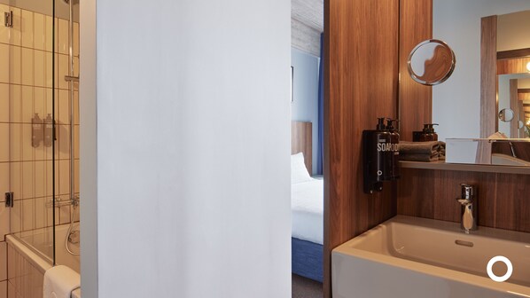 A bathroom with a shower, a sink, and a mirror.
