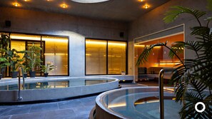A modern indoor pool area with glass walls and warm lighting.