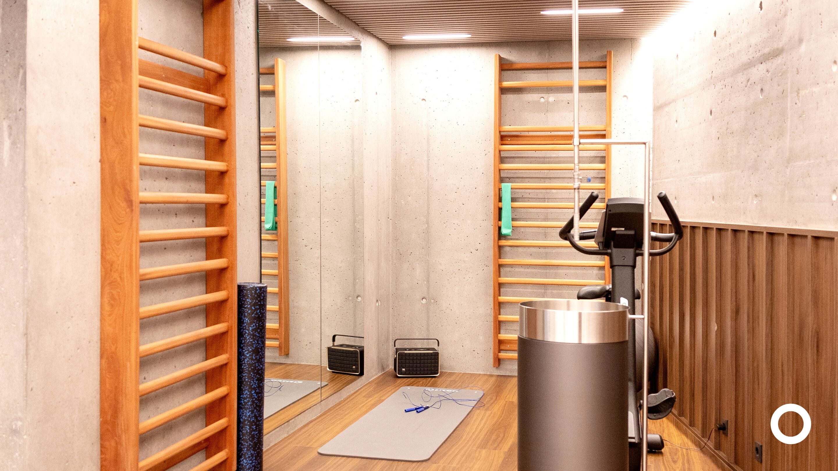 A gym with wooden walls, exercise equipment, and a mirrored wall.