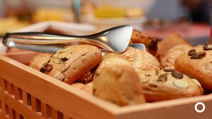 Een houten mand gevuld met verschillende soorten brood, waaronder brood met zaden en noten.