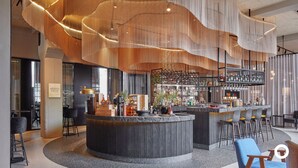 Un espace bar moderne doté d’un comptoir incurvé, de tabourets de bar et d’une variété de bouteilles et de verres.
