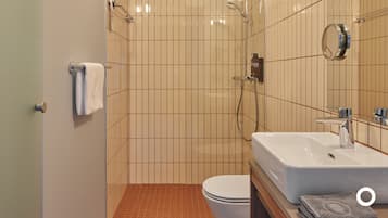 A bathroom with a shower, toilet, sink, and mirror.