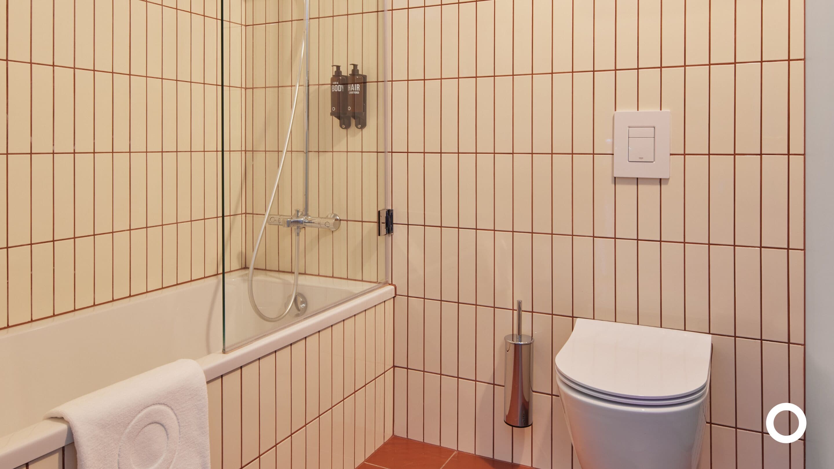 A bathroom with a glass-enclosed shower, a toilet, and a towel rack.