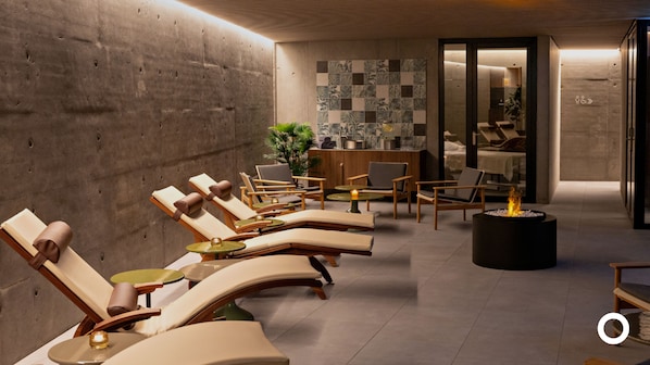 A modern lounge area with lounge chairs, a small fire pit, and a reception desk.