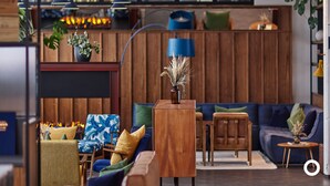 Un salon chaleureux avec un canapé en bois, une petite table d’appoint et une lampe décorative.
