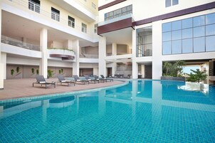 Una piscina al aire libre, sillones reclinables de piscina