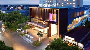 Un hotel moderno con un letrero llamativo, una entrada bien iluminada y vistas de la ciudad circundante.