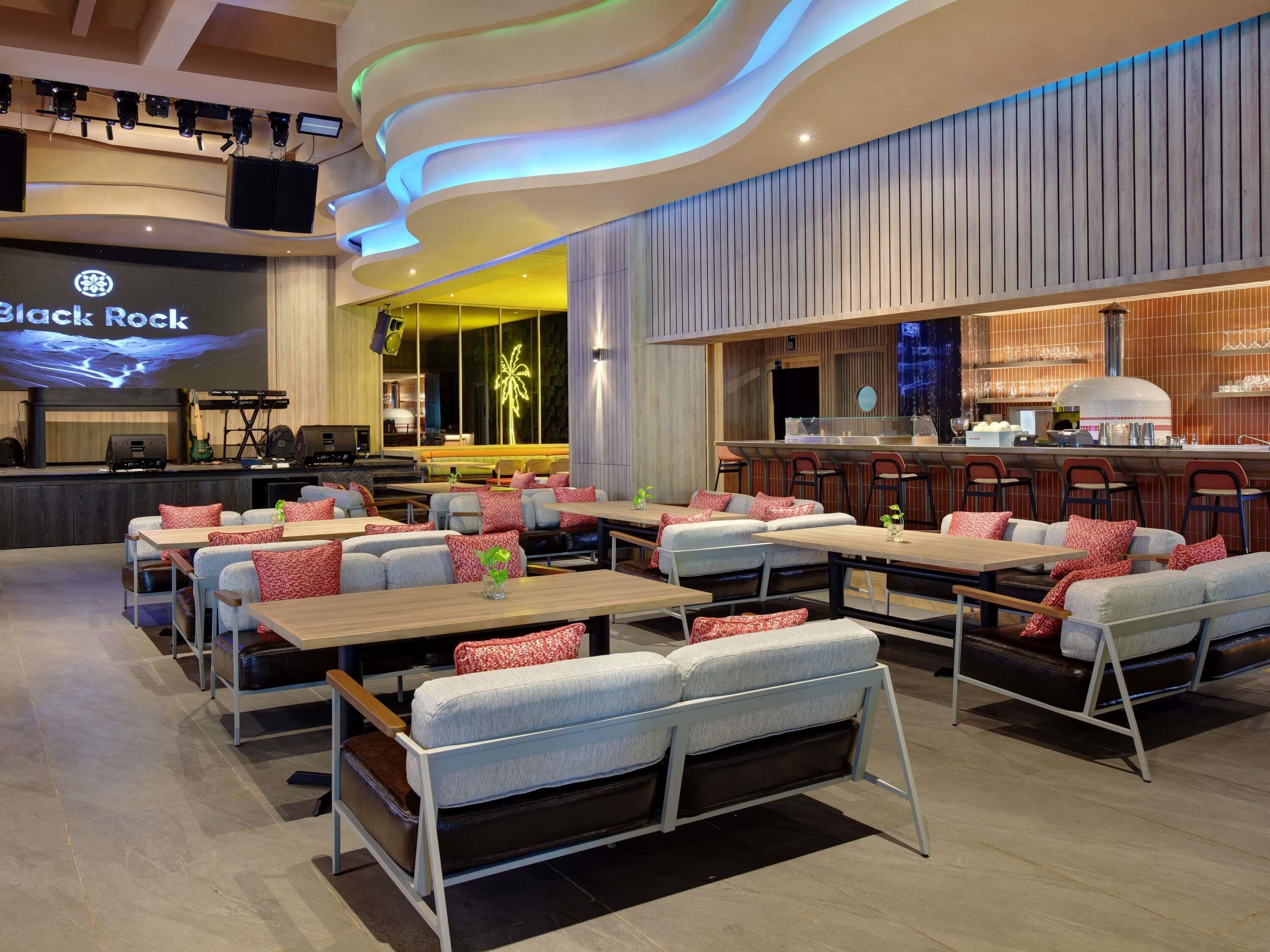 A modern restaurant interior with a stage, bar area, and seating arrangements.