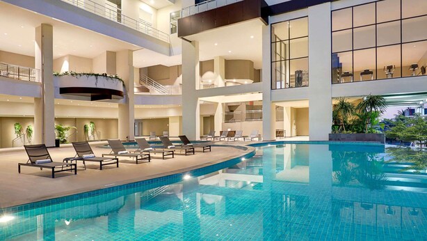 Piscina interior de varios niveles con sillones reclinables y plantas en macetas.