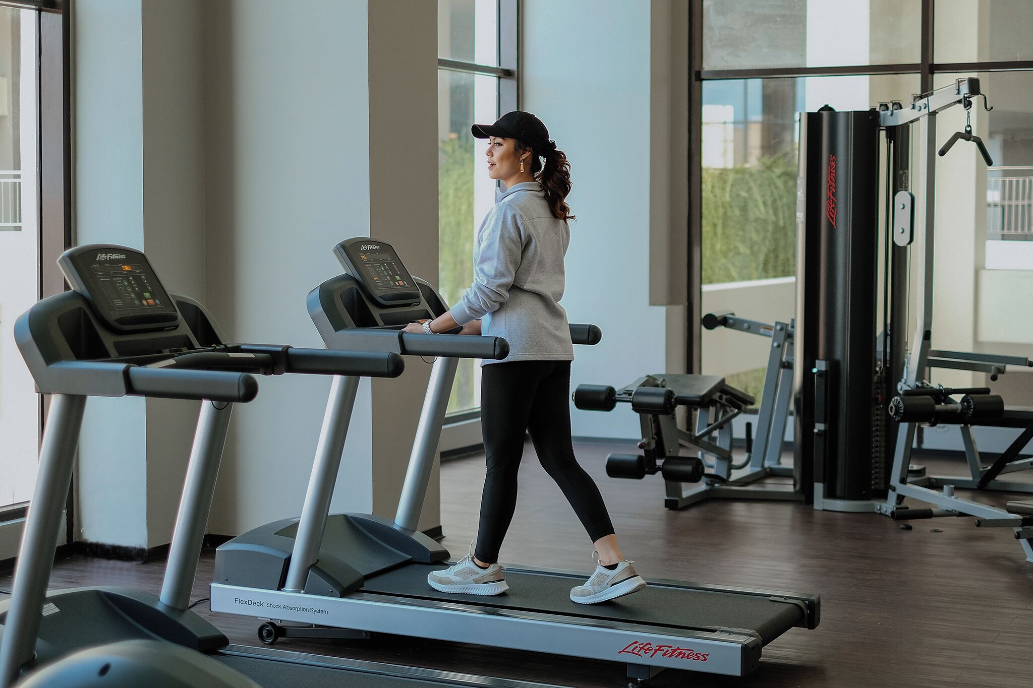 A person walking on a treadmill in a gym with various exercise equipment in the background.