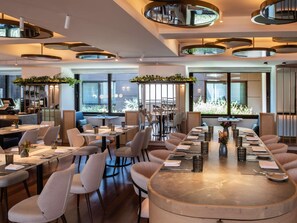 A modern dining area with round tables, chairs, and ceiling lights.