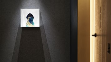 Quarto com piso texturizado escuro, uma obra de arte com moldura branca na parede e uma porta de madeira com puxador.