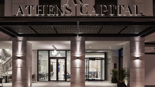 The exterior of Athens Capital hotel with a modern facade, large columns, and a well-lit entrance. - Athens Capital Center Hotel-MGallery Collection (Athens)