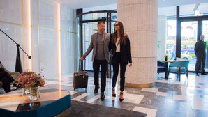 A modern lobby with a reception desk, a large pillar, and a check-in counter. - Athens Capital Center Hotel-MGallery Collection (Athens)
