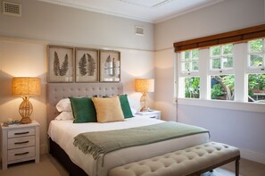 Classic design bedroom with a large bed, bedside tables, and framed prints.