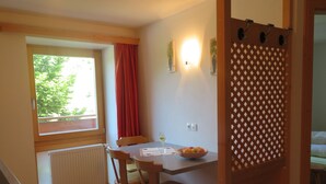 A small dining area with a table, chairs, a bowl of fruit, and a window with a view of greenery. - Holiday apartment valley view (Curon Venosta)