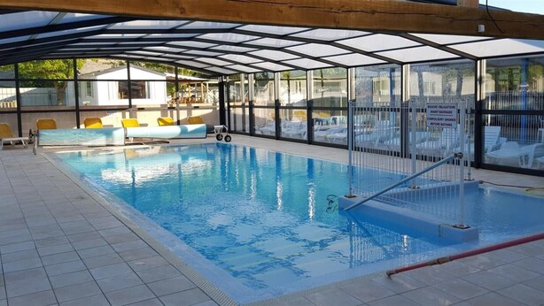An indoor swimming pool with a glass enclosure, tiled floor, and yellow lounge chairs. - ---- bungalow 5 ---- (Les Mathes)