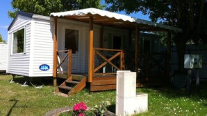 A mobile home with a porch and a small garden area with flowers. - ---- bungalow 5 ---- (Les Mathes)