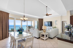 Un grand espace de vie avec un balcon, une table à manger, un canapé et un téléviseur.