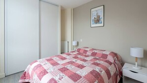 Un dormitorio con cama, mesita de noche, lámpara, radiador y puerta.