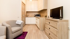 A compact living space with a sofa, a television, a kitchen area with cabinets, and a small island.